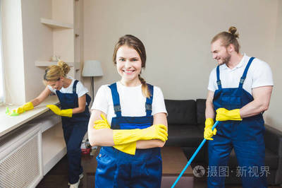 在工作過程中使用專業(yè)設(shè)備的清潔服務(wù)。專業(yè)的小廚房清潔, 沙發(fā)干洗, 窗戶和地板清洗。穿制服、工作服和橡膠手套的男人和女人